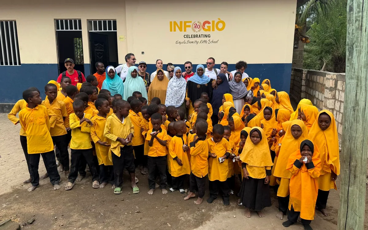 Gruppo di bambini e volontari davanti alla scuola